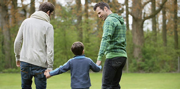Same sex parents with boy in park