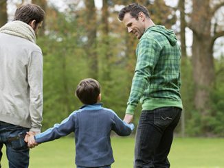 Same sex parents with boy in park